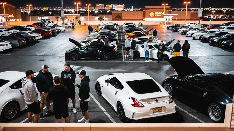 Rows of cars and a crowd at a night car meet with the Las Vegas Strip glowing behind